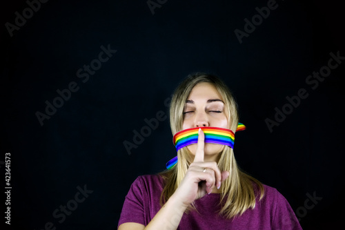 Conceptual image of censorship and social taboo on the LGBT community. Woman with lgbt tape wrapped around her mouth photo