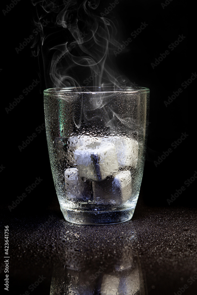 stainless steel cubes simulating ice in whisky glass on a black table. stainless steel cubes simulating ice in whisky glass on a black table.