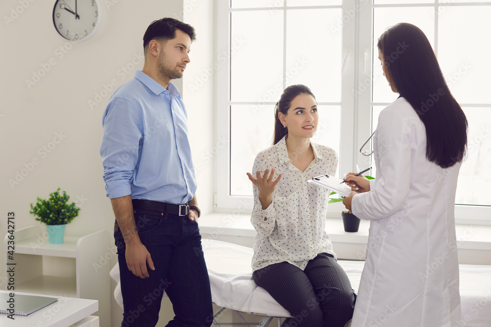 Fototapeta premium Gynecology consultation. Worried woman and her husband tell a female doctor at a fertility clinic about their problems. Concept of infertility, childbirth, motherhood and child, new life or abortion.