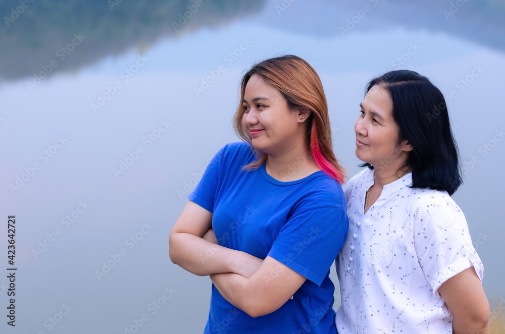 Single asian mother and her teenager daughter standing on lake background with shadow of mountain. Mother day concept Single asian mother and her teenager daughter standing on lake background with shadow of mountain. Mother day concept