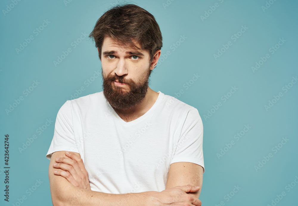 a man in a white t-shirt on a blue background gestures with his hands sad look a man in a white t-shirt on a blue background gestures with his hands sad look