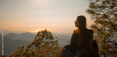 Hermosa mujer sentada sobre piedra en montaña pensando vestida de negro y con gafas de sol, cerro de la bufa Vallarta Jalisco 