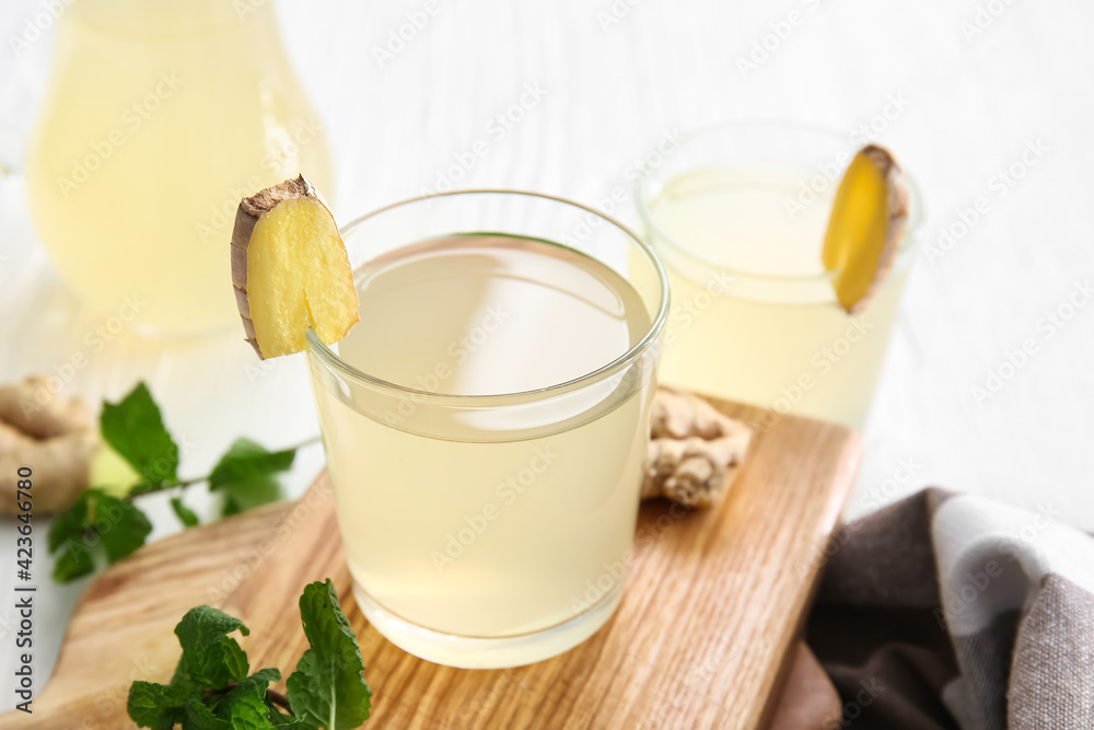 Board with glass of healthy ginger juice on light background Board with glass of healthy ginger juice on light background