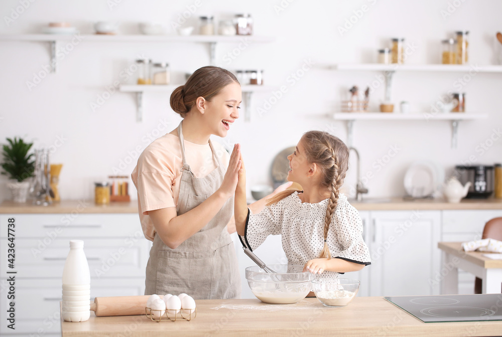 Happy woman and her little daughter cooking in kitchen Happy woman and her little daughter cooking in kitchen