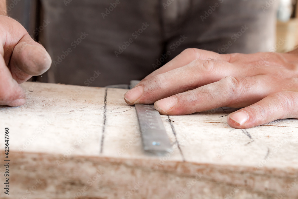 Male carpenter working with wood material in a garage. Male carpenter working with wood material in a garage.