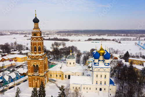 Scenic view from drone of temple complex of Cathedral of Archangel Michael and Church of Jerusalem Icon of Mother of God with Bronnitsy cityscape on background in winter, Russia.. photo