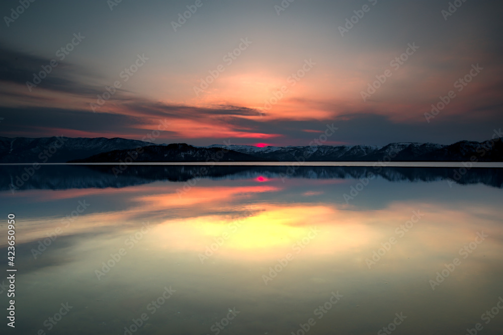雲の向こうに陽の沈む空を水面に映す黄昏の湖。日本の北海道の屈斜路湖。