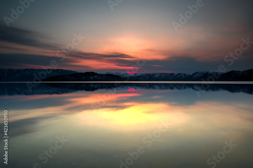 雲の向こうに陽の沈む空を水面に映す黄昏の湖。日本の北海道の屈斜路湖。