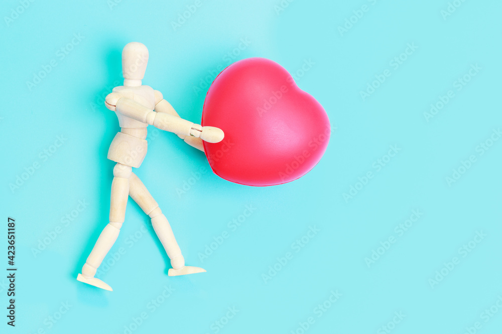 Wooden man holding heart shape on blue background, copy space Wooden man holding heart shape on blue background, copy space