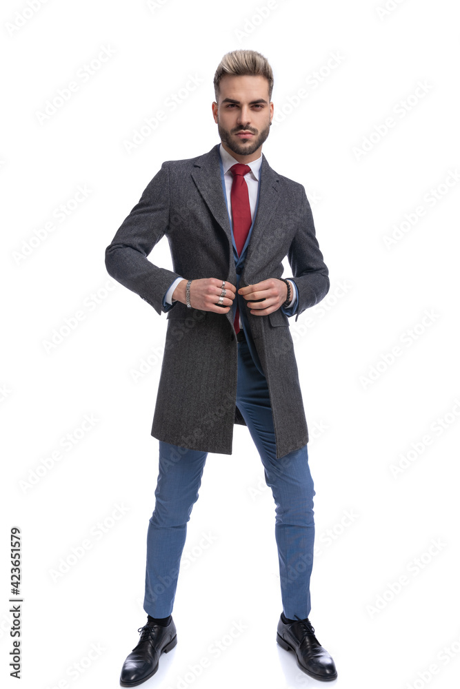 full body picture of elegant businessman in blue suit buttoning long coat full body picture of elegant businessman in blue suit buttoning long coat