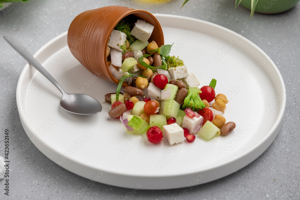 fresh green salad served on a white plate with beans, legumes, and pomegranate seeds fresh green salad served on a white plate with beans, legumes, and pomegranate seeds