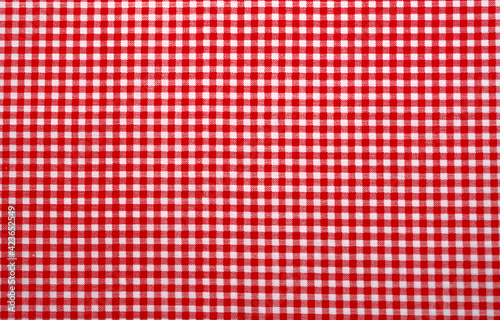 Red and white checkered tablecloth. Top view table cloth texture background. Red gingham pattern fabric. Picnic blanket texture. Red table cloth for Italian food menu. Square pattern of gingham.