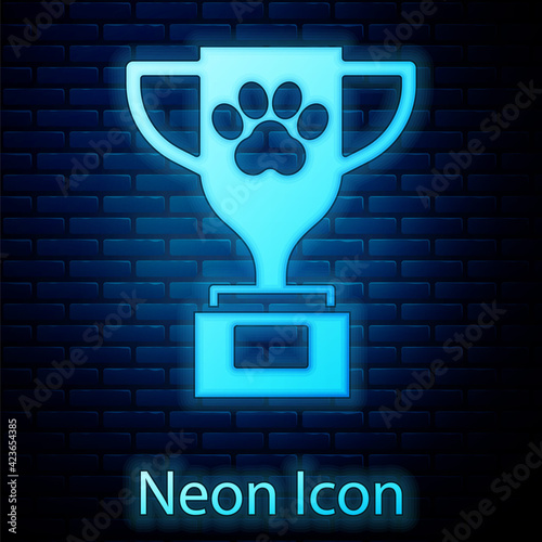 Glowing neon Pet award symbol icon isolated on brick wall background. Medal with dog footprint as pets exhibition winner concept. Vector