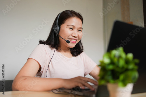 close up young asian woman call center talking on microphone headset to assist and consult colleagues or customer at home office in lockdown and quarantine time for work from home concept photo