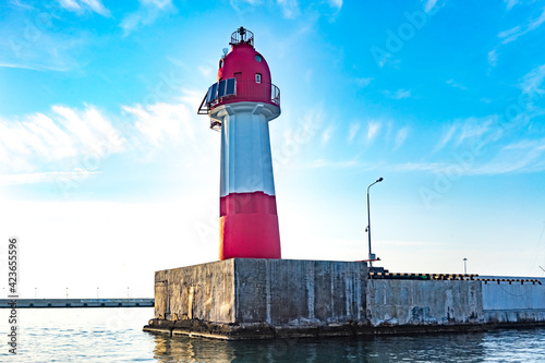 Navigation lighthouse tower on the breakwater in the seaport. © vvicca