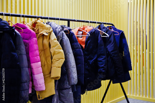 Interior of room storing outdoor clothing for visitors of the establishment, with yellow backgrounds. Wardrobe, many hangers clothes institution, leave outerwear, undress pass into room. Copy space