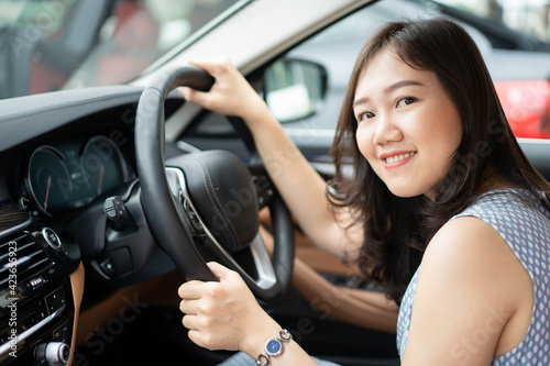 Happy Asian young woman driver sitting on the driver seat in the luxury modern car