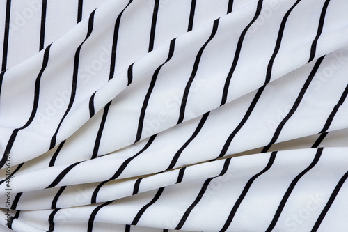 Fragment of a striped wrinkled black and white piece of a cloth fabric.