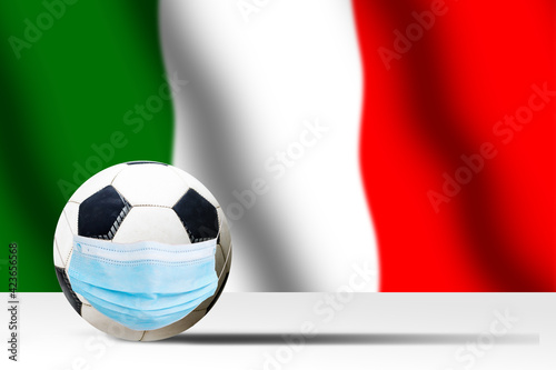 Soccer ball in a medical mask against the background of the flag of italy. Corona protection against viruses bacteria stop. Cancellation of sporting events. Copy space