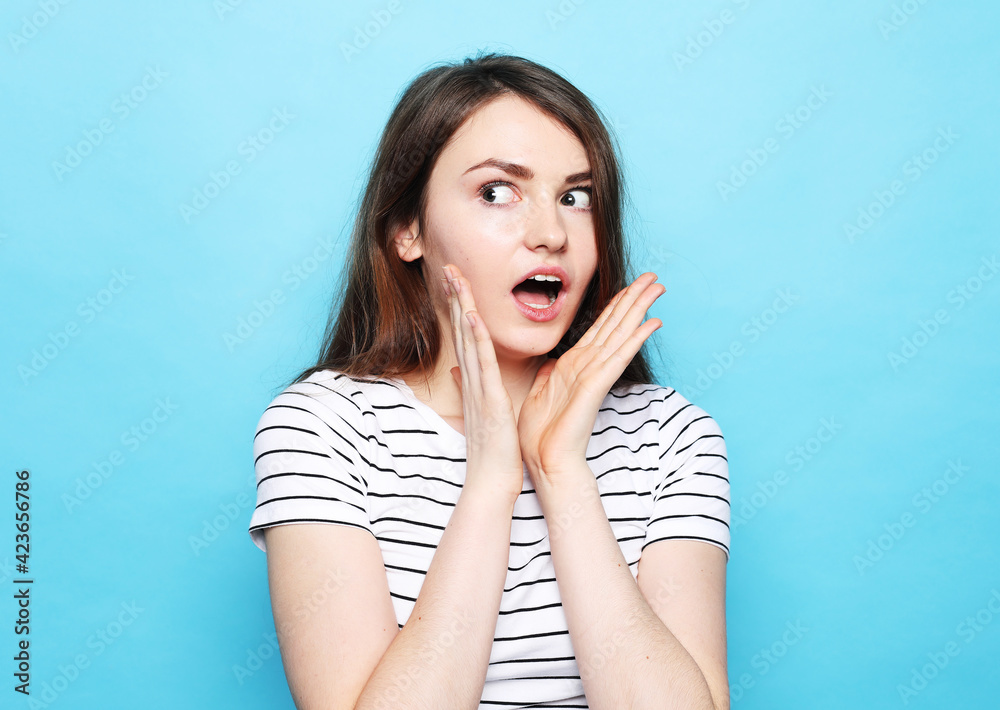 Portrait of a funny young woman, dressed in a striped T-shirt with arms outstretched, in surprise and amazement. Portrait of a funny young woman, dressed in a striped T-shirt with arms outstretched, in surprise and amazement.