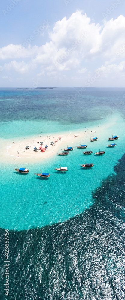 Obraz premium View from above or from a bird's eye view of the coral island, the white sand beach and the beautiful, clear turquoise waves with boats.