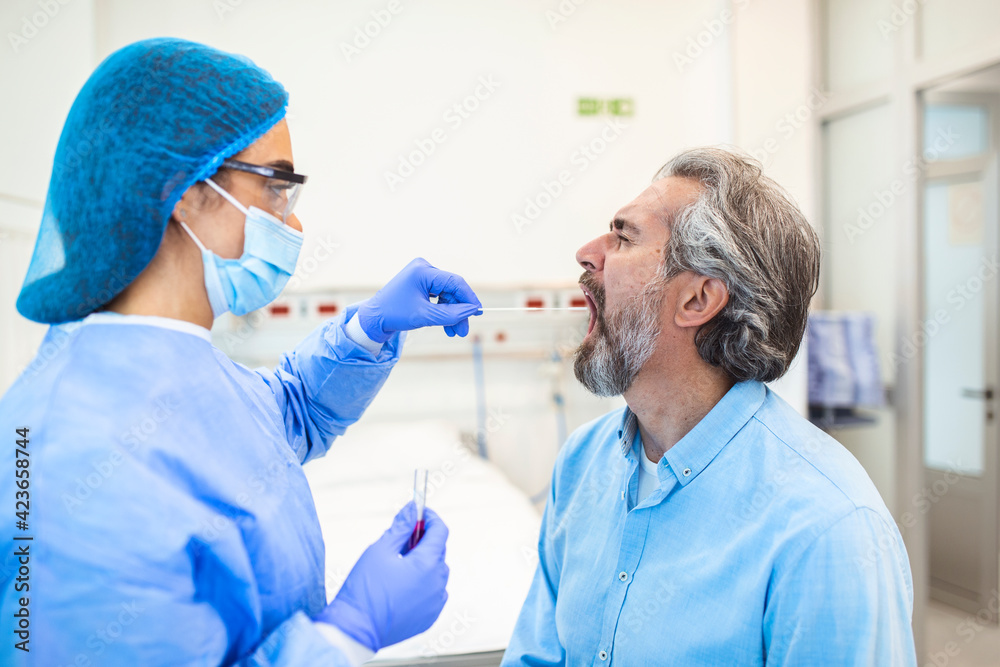 A mature Caucasian man in a clinical setting being swabbed by a healthcare worker in protective garb to determine if he has contracted the coronavirus or COVID-19. PCR test A mature Caucasian man in a clinical setting being swabbed by a healthcare worker in protective garb to determine if he has contracted the coronavirus or COVID-19. PCR test