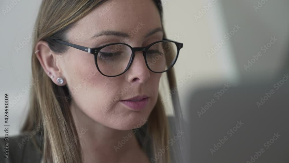 Woman with eyeglasses working on laptop computer from home Woman with eyeglasses working on laptop computer from home