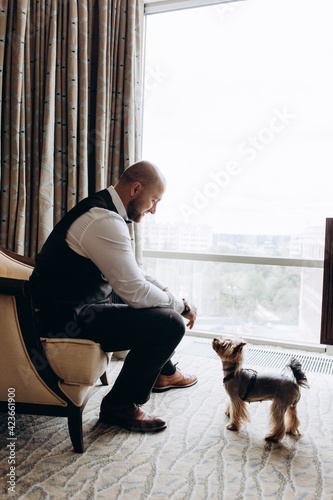 Portrait of the groom. The groom is preparing to meet the bride. Photo with a small dog.