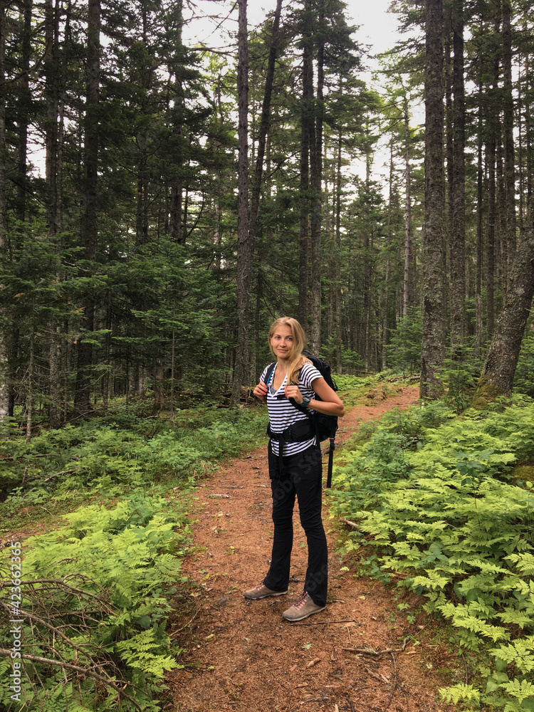 Hike to the forest in autumn. A young girl goes to the mountains with a backpack.