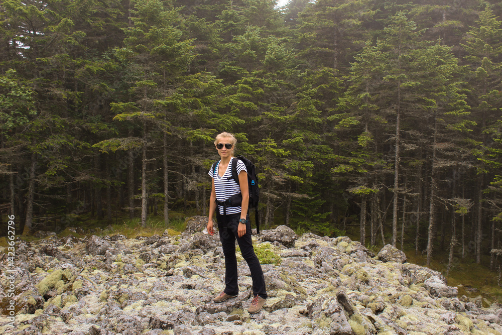 Hike to the forest in autumn. A young girl goes to the mountains with a backpack.