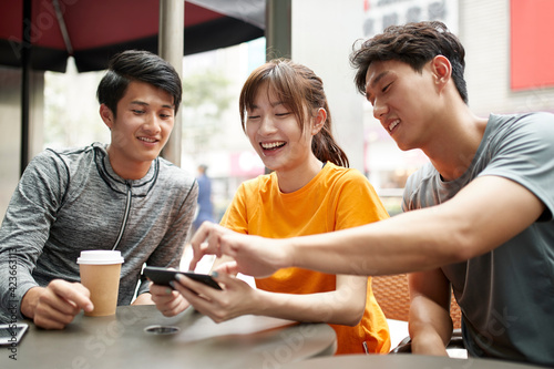 young asian adults looking at cellphone photo