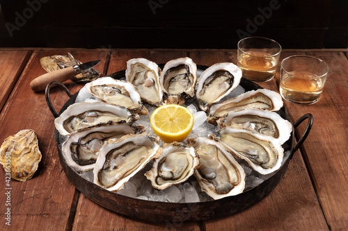 Oysters on a rustic table. A dozen of fresh oysters with lemons and wine