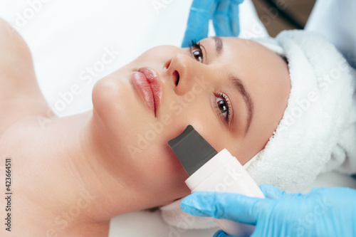 Beautiful woman receiving ultrasonic face cleaning in beauty salon