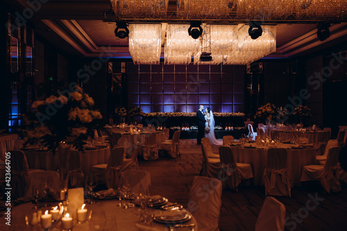 The bride and groom in a large banquet hall.