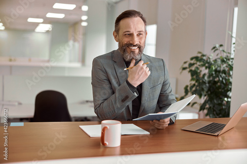 Happy adult caucasian man is working in a modern office