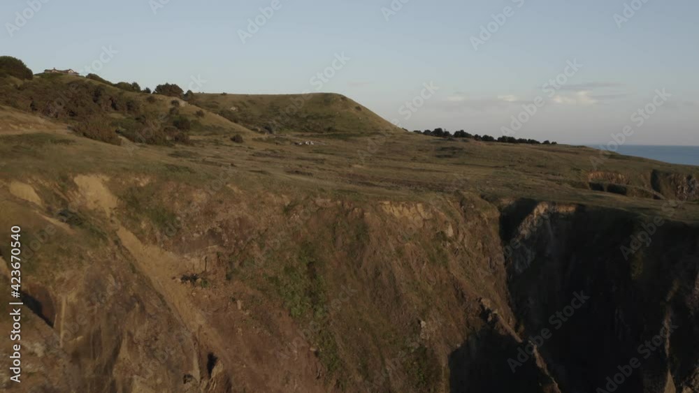 Coastal cliffs and grassy hillside at sunset Coastal cliffs and grassy hillside at sunset