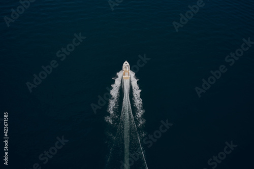 Large speed boat moving at high speed. Top view of a white boat sailing to the blue sea. Drone view of a boat sailing. Motor boat in the sea. Travel - image.