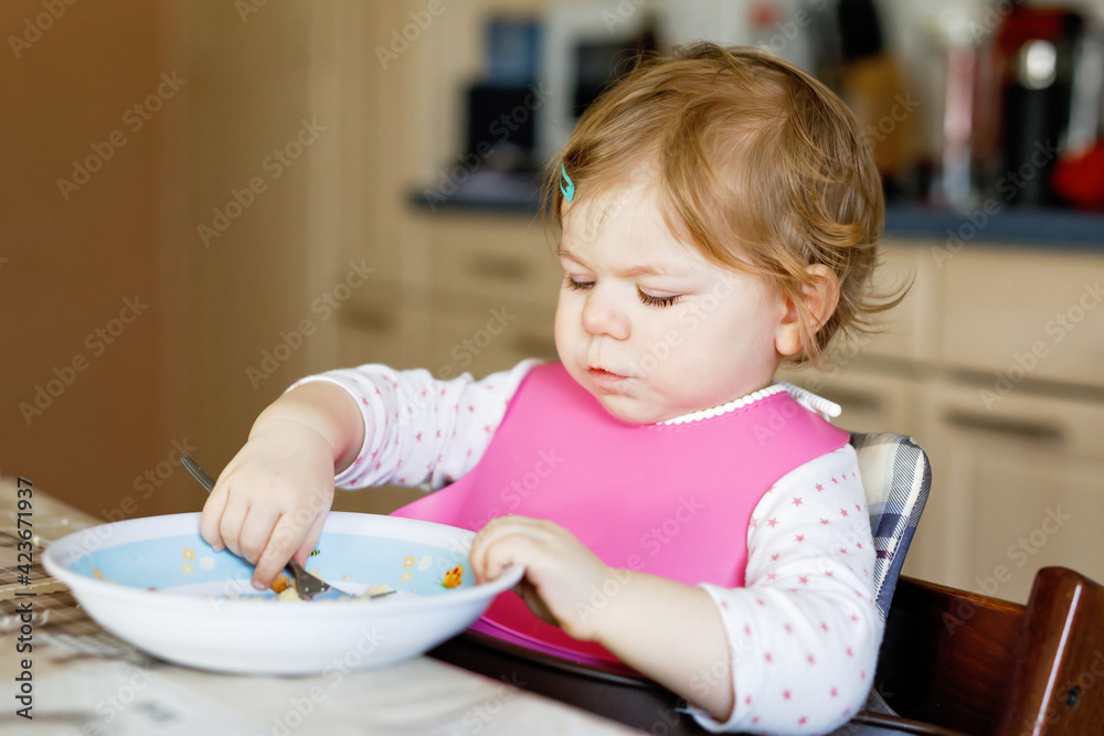 Adorable baby girl eating from spoon mashed vegetables and puree. food, child, feeding and people concept Adorable baby girl eating from spoon mashed vegetables and puree. food, child, feeding and people concept