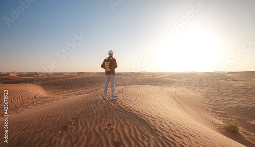 Desert adventure. Young man with backpack walking on sand dune. Dubai  United Arab Emirates