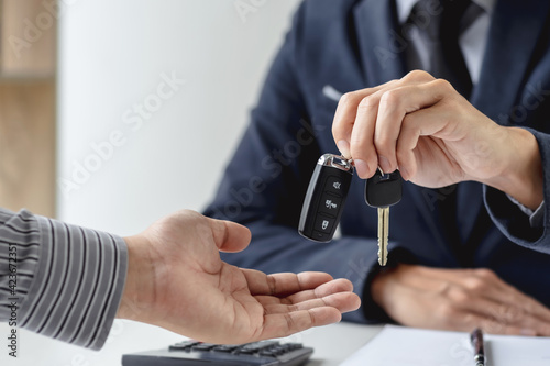 Businessman agent holding car keys offering new car salesman Automobile Vehicles Concept