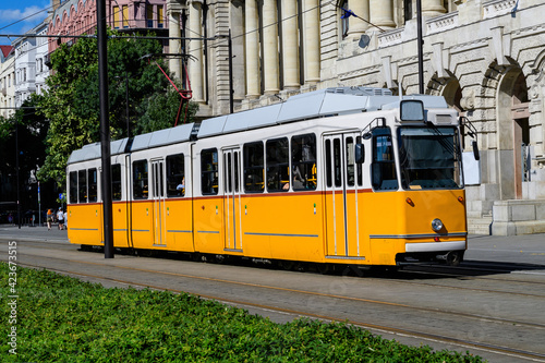 Historic yellow tram for passengers driving through the streets and part of the public transport system in in the old center in a sunny summer day.
