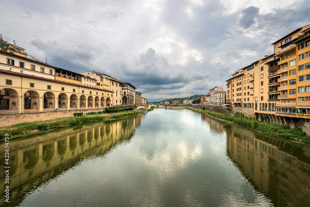Florence. Arno River view from the Medieval Ponte Vecchio (Old Bridge). On the left the Vasari Corridor (Corridoio Vasariano, 1565), which connects Palazzo Vecchio with Palazzo Pitti. Tuscany Italy.