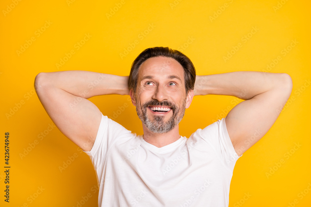 Portrait of attractive cheerful virile guy looking up copy space resting isolated over bright yellow color background Portrait of attractive cheerful virile guy looking up copy space resting isolated over bright yellow color background