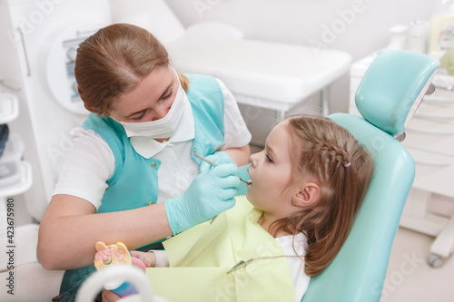 Female dentist checking teeth of a little girl