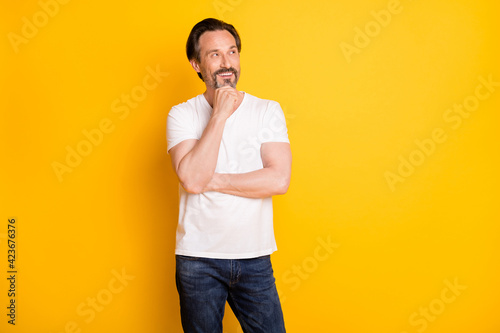 Portrait of attractive cheerful guy wearing casual creating solution isolated over bright yellow color background