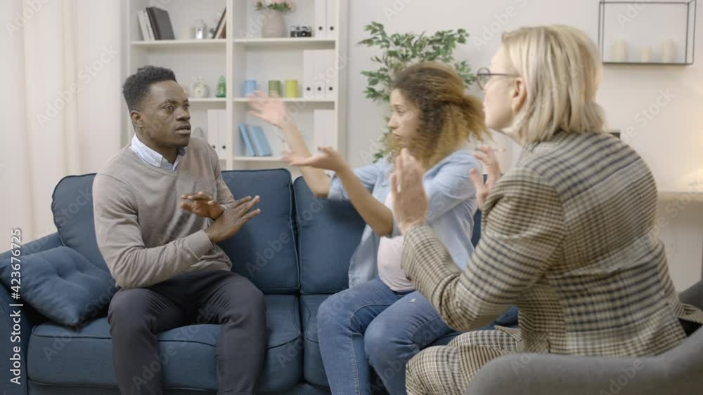 Professional therapist calming arguing couple in counseling session, conflict Professional therapist calming arguing couple in counseling session, conflict