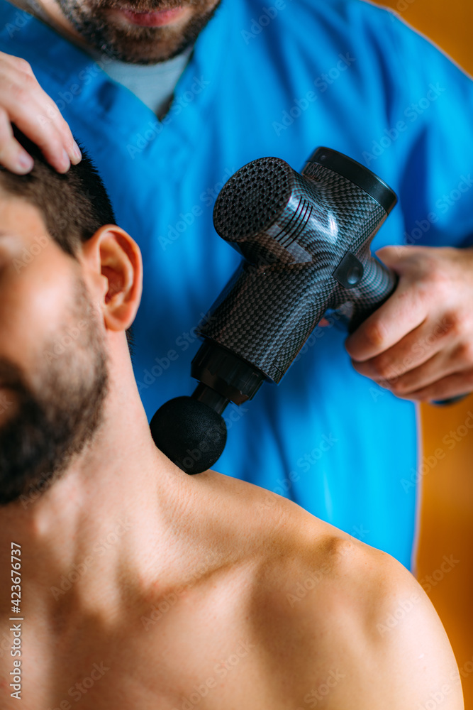 Therapist Treating Patient’s Trapezius Muscle with Massage Gun Stock