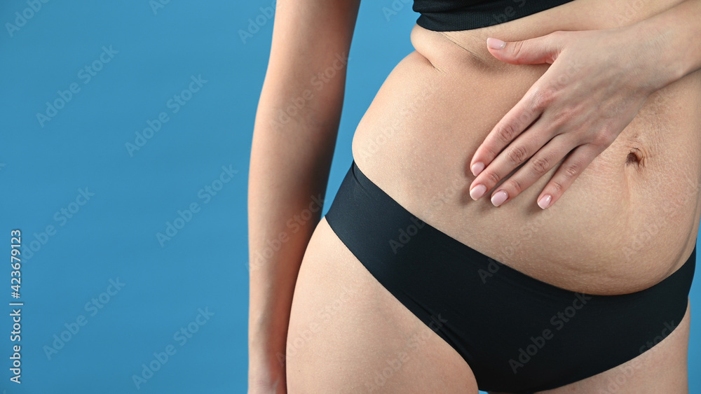 Woman in panties is standing sideways and shows folds of waist fat on blue background. Weight loss Woman in panties is standing sideways and shows folds of waist fat on blue background. Weight loss