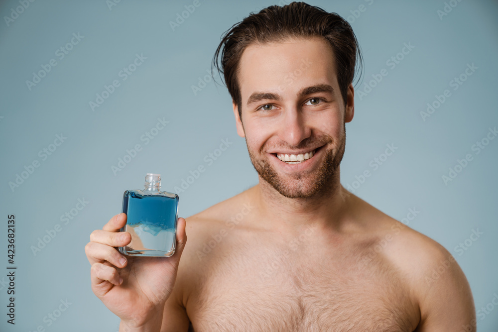 Shirtless white man smiling while showing cologne Shirtless white man smiling while showing cologne