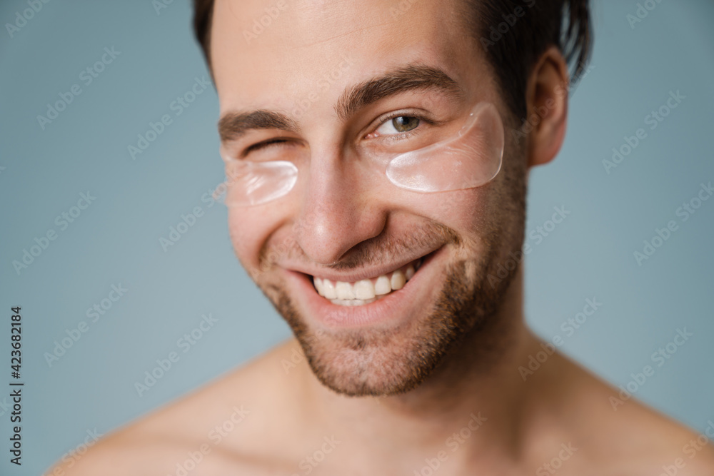 Shirtless white man with under eye patches winking at camera Shirtless white man with under eye patches winking at camera